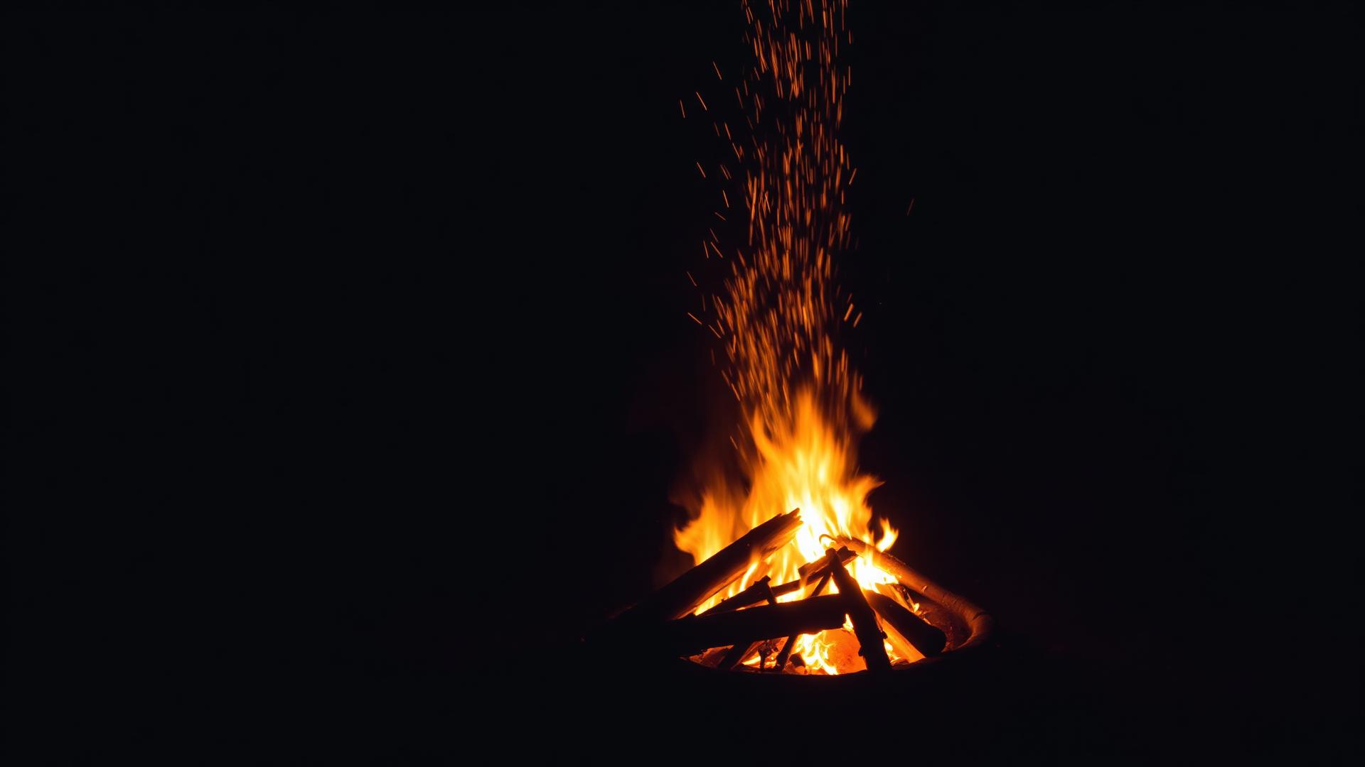 Evening bonfire with embers rising into the dark
